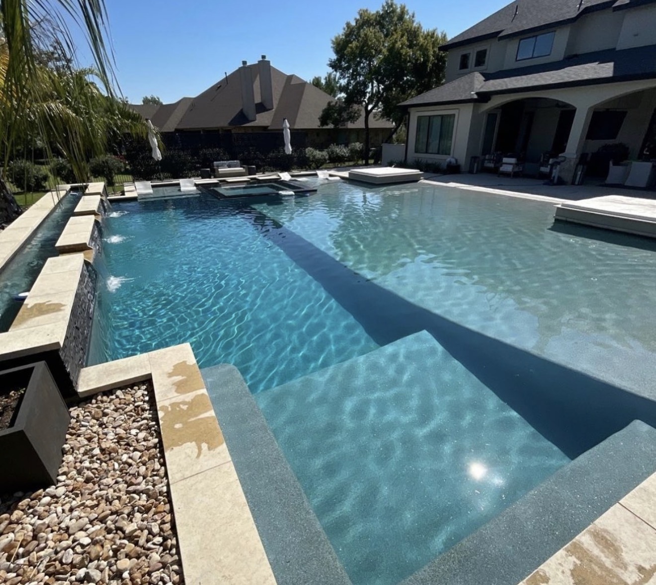 Modern pool with sun shelf, spa and travertine deck